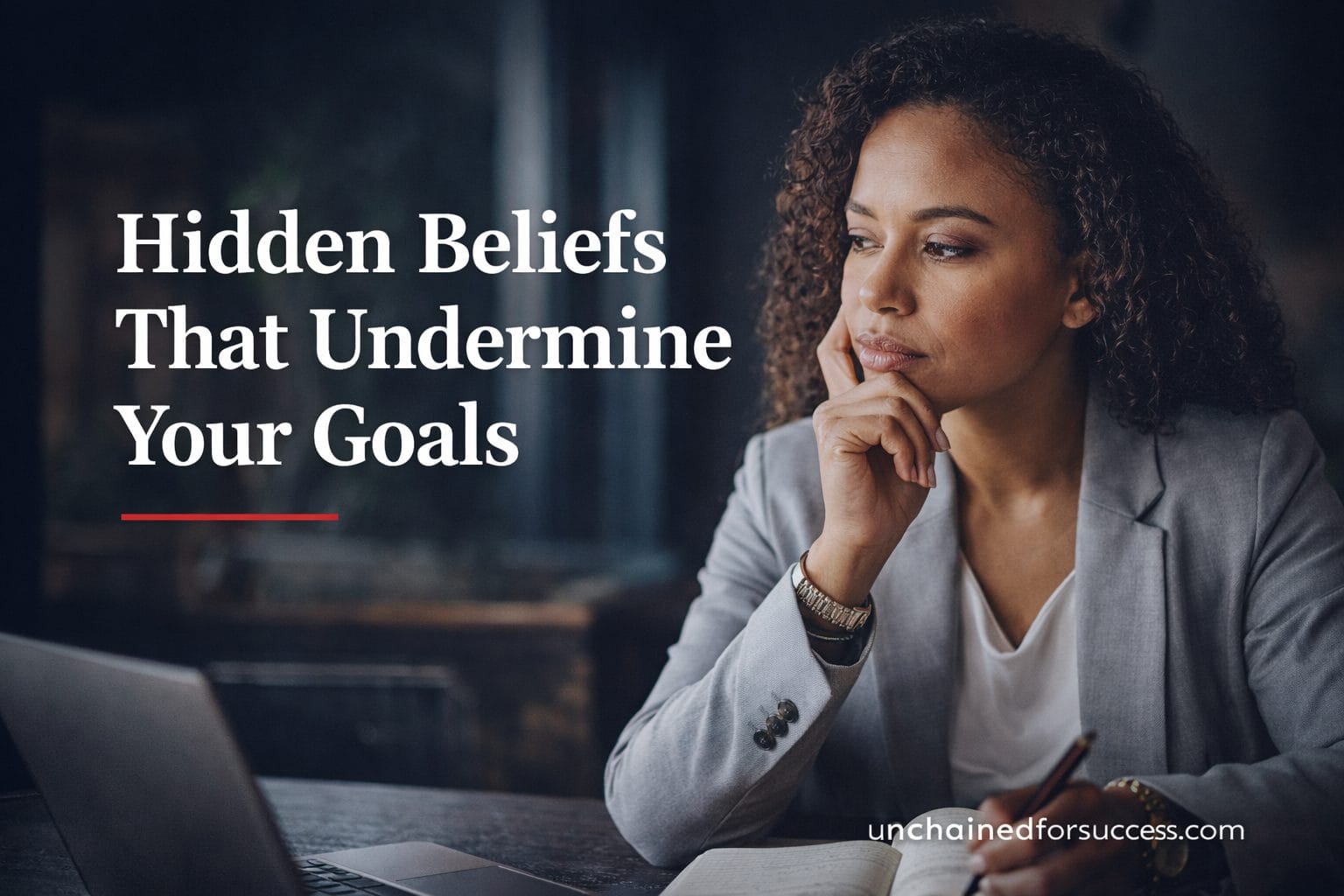 Mixed race professional woman reflecting at desk with Hidden Beliefs That Undermine Your Goals blog title overlay